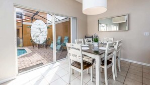 A dining area with a glass door leading to a patio, a pool, and a modern interior with a large mirror and pendant light. - 101 Perfect Family Townhouse With Private Pool Near Disney Water Parks (Kissimmee)