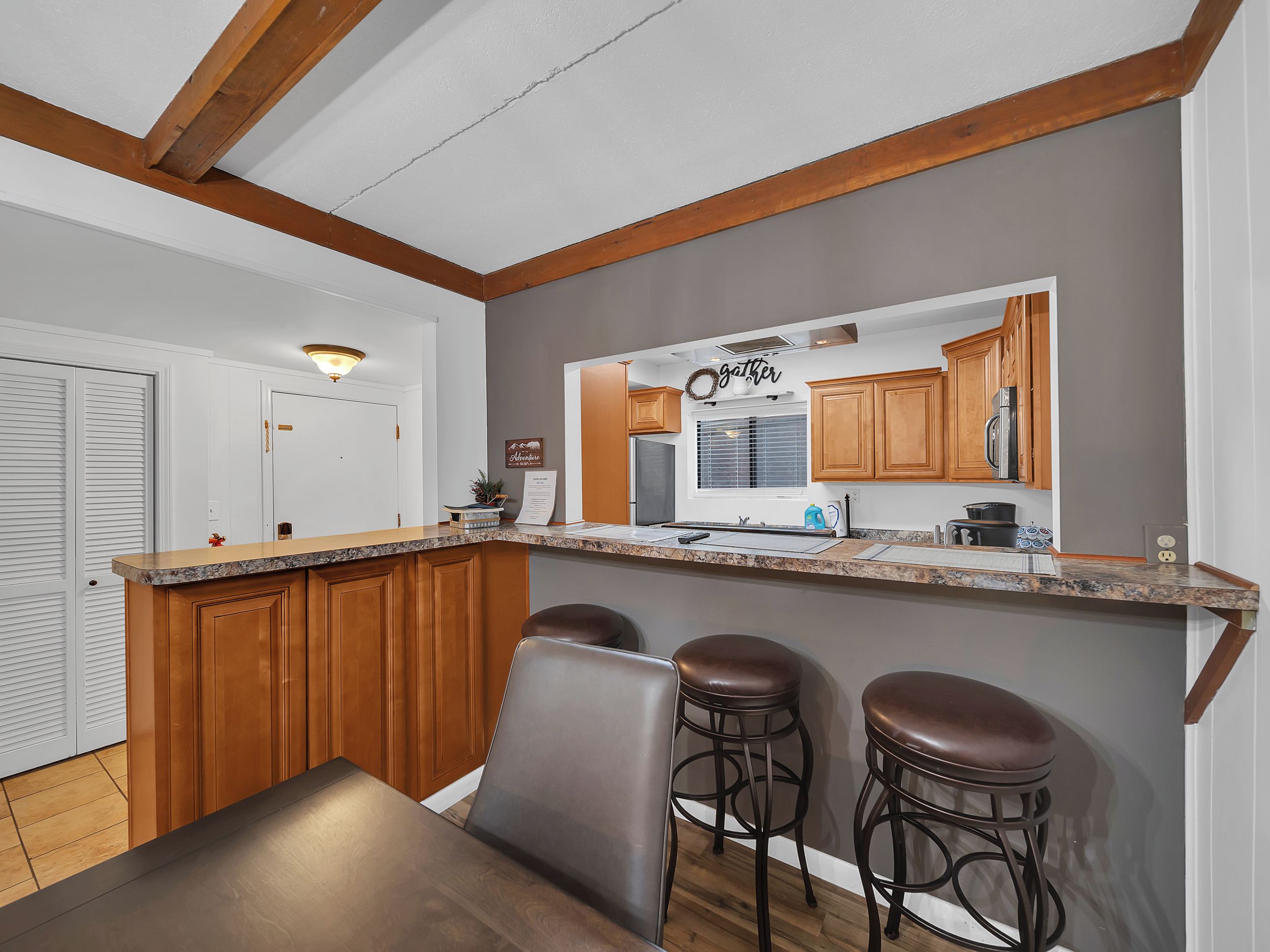 A kitchen with wooden cabinets, a granite countertop, and a bar area with stools.