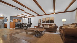 Amplia sala de estar con techo de madera, una mesa de comedor y un sofá.