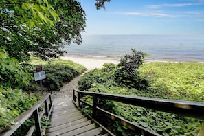 Una escalera de madera que lleva a una playa con vista clara al océano.