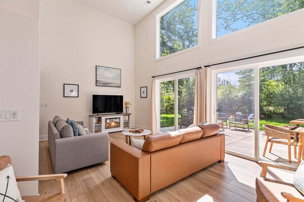 Ein modernes Wohnzimmer mit Kamin, Fernseher und einer großen Schiebeglastür, die auf eine Terrassenausläufer führt.