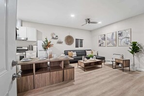 A modern living room with a sofa, coffee table, and dining area. - Ocean View Home Near Beach with Private Patio (San Diego)