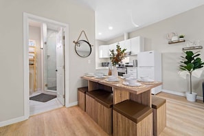 Una cocina moderna con armarios blancos, una isla central con taburetes y un espejo colgante.
