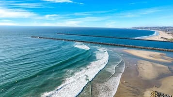 Eine Küstenlandschaft mit Wellen, einem Sandstrand und blauem Himmel.