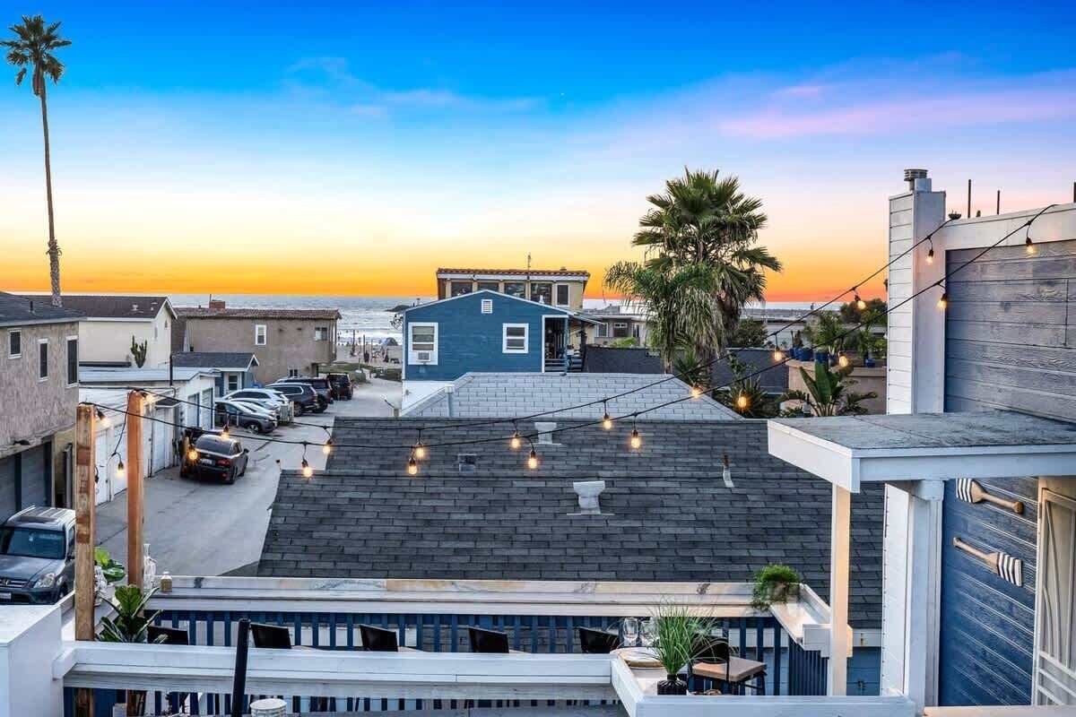 Un quartier résidentiel avec une maison bleue, des voitures garées et un ciel dégagé.