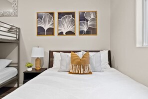 A hotel room with a bunk bed, a bedside table with a lamp, and three framed wall art pieces. - Ocean View Home Near Beach with Private Patio (San Diego)