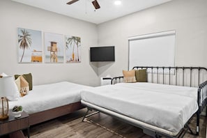 A hotel room with two beds, a TV, and artwork on the wall.