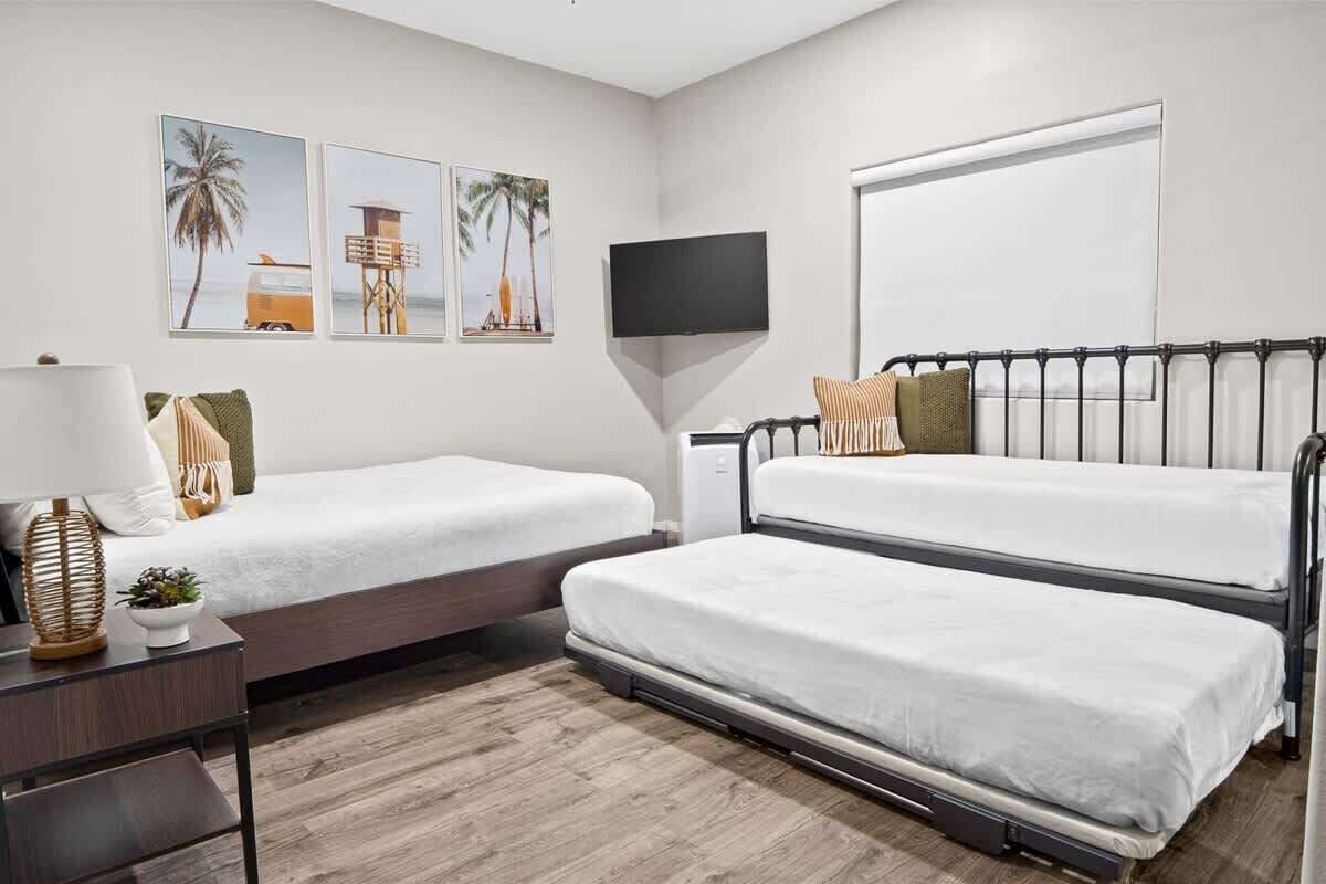 Ein Zimmer mit zwei Betten, einem Fernseher und Bildern an der Wand.
