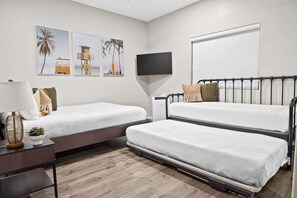Une chambre avec deux lits, une télévision et des œuvres d’art accrochées au mur.