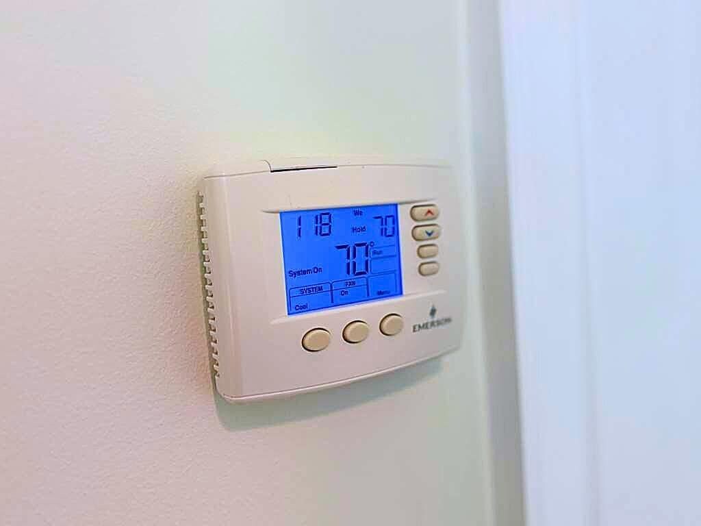 A digital thermostat mounted on a wall.