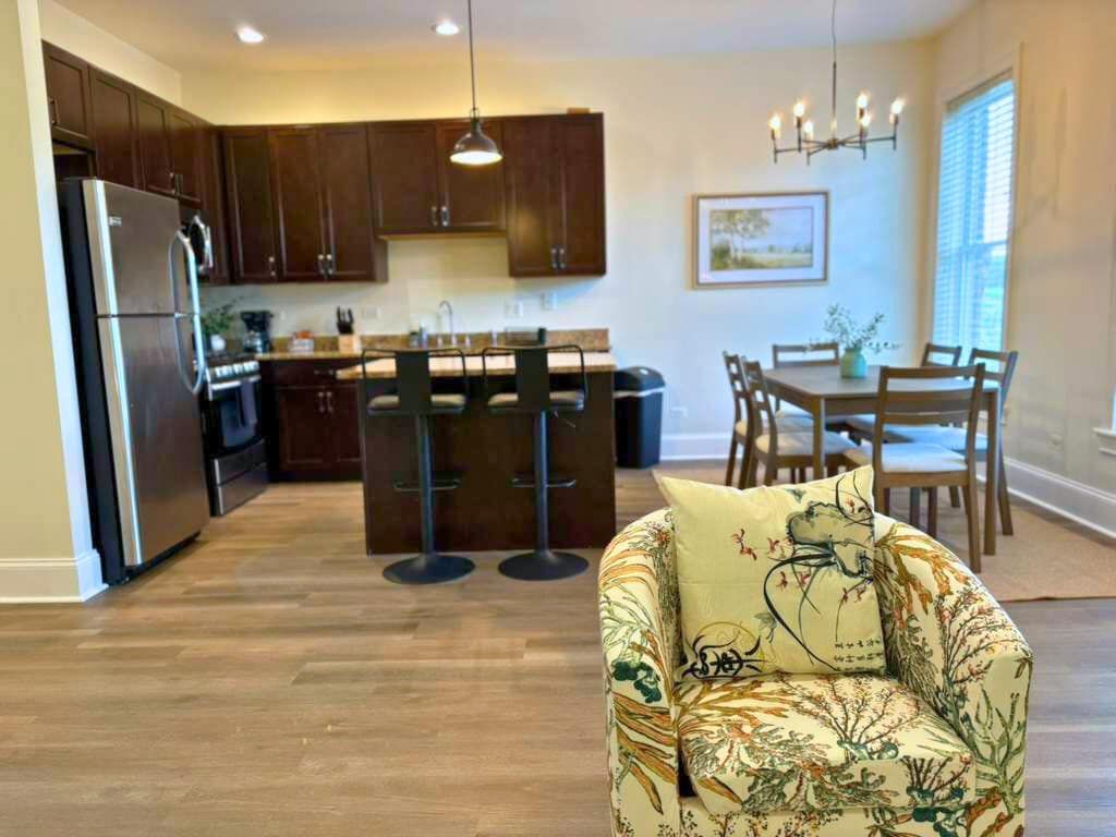 Eine moderne Küche mit dunklen Holzschränken, einem Edelstahlkühlschrank und einem Essbereich mit Tisch und Stühlen.