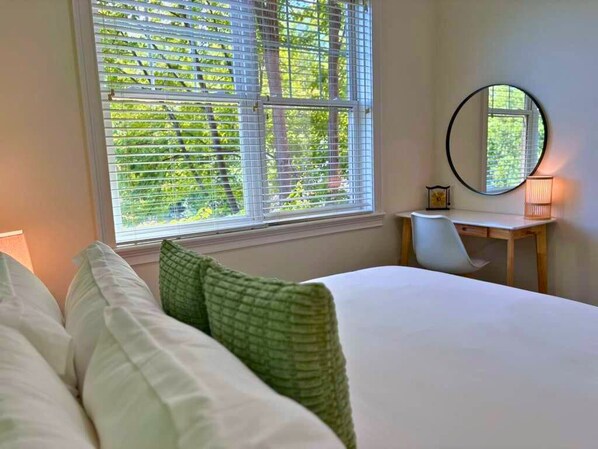 A bedroom with a bed, a desk, and a window with blinds.