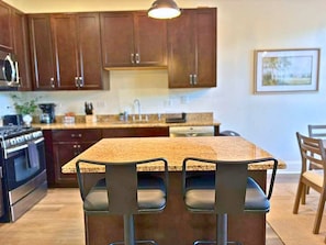 A kitchen with wooden cabinets, a granite countertop, and a bar stool.