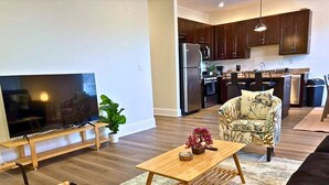 A modern living room with a flat-screen TV, a wooden coffee table, and a patterned armchair. - Well-Equipped 2BR Unit with Parking (Evanston)