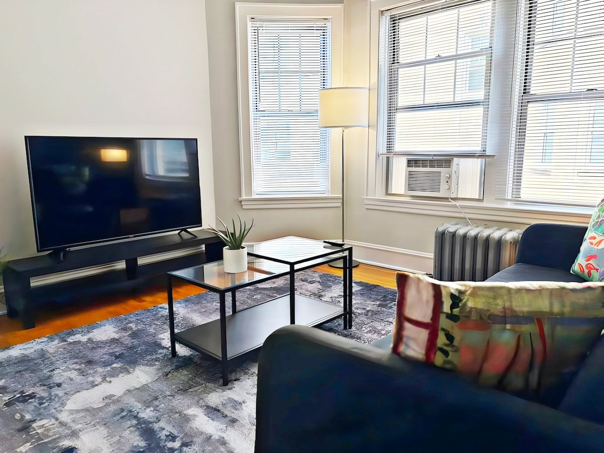 A living room with a flat-screen TV, a coffee table, a sofa, and a radiator.