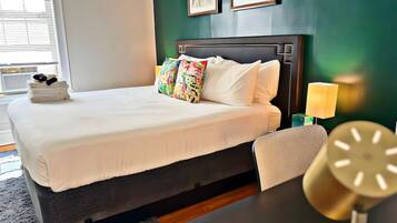 Una habitación de hotel con una cama, una silla, una mesita de noche y una lámpara.