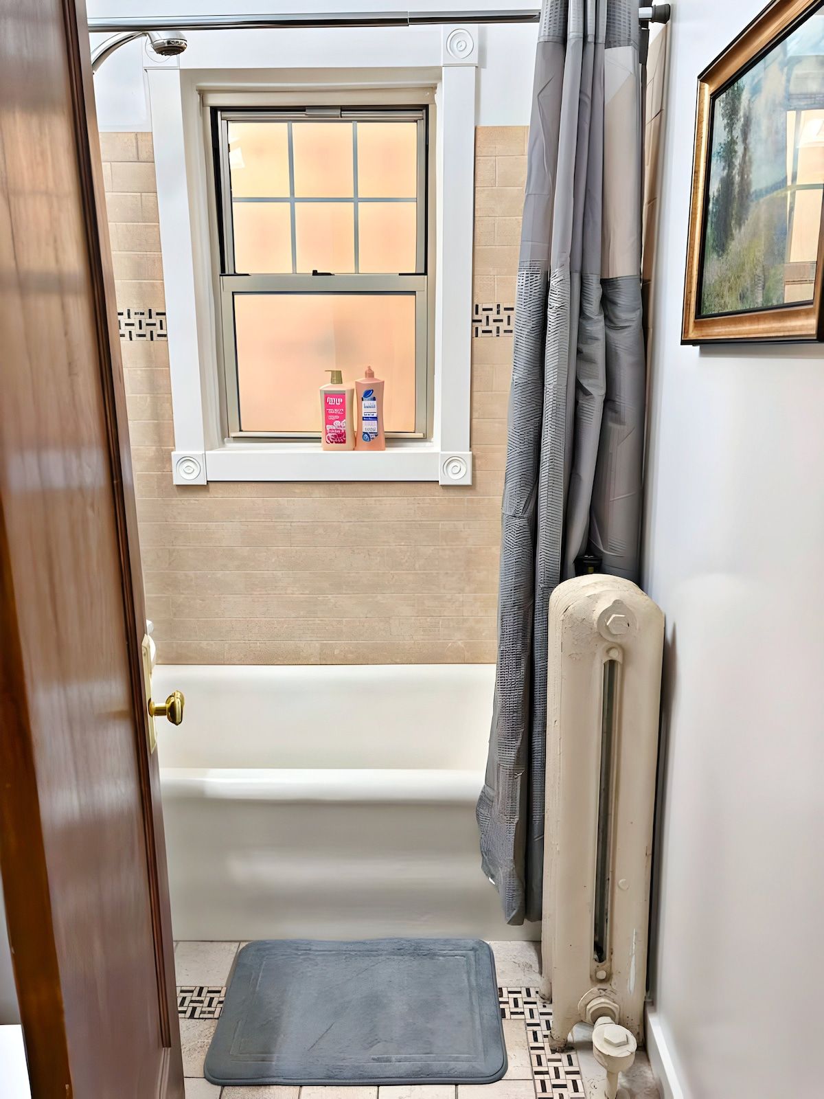 Une salle de bain avec une baignoire, une fenêtre donnant sur un paysage agréable, un radiateur et une porte.