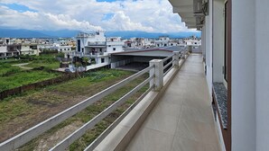 Uma varanda com vista para um horizonte urbano, incluindo edifícios e montanhas ao longe.