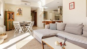 A modern living room with a sofa, a coffee table, and a dining area with chairs and a table.