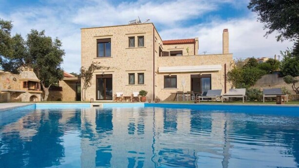 A two-story stone building with a swimming pool in front.