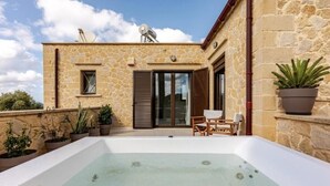 A stone building with a hot tub, outdoor seating, and potted plants.