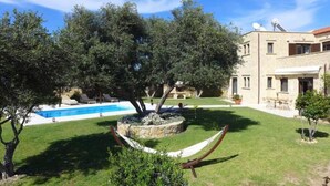 A pool with a stone surround, a hammock, and a building with satellite dishes.