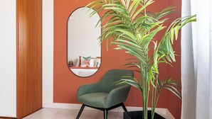Una habitación con un sillón verde, un espejo grande y una planta en maceta.