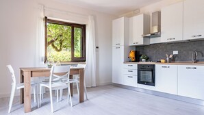 Una cocina moderna con armarios blancos, una mesa de comedor de madera y sillas.