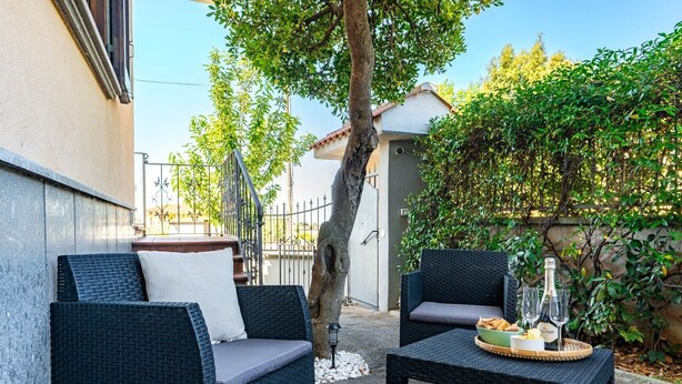 Un área de estar al aire libre con mobiliario de mimbre y una mesa dispuesta con pan y copas de vino.