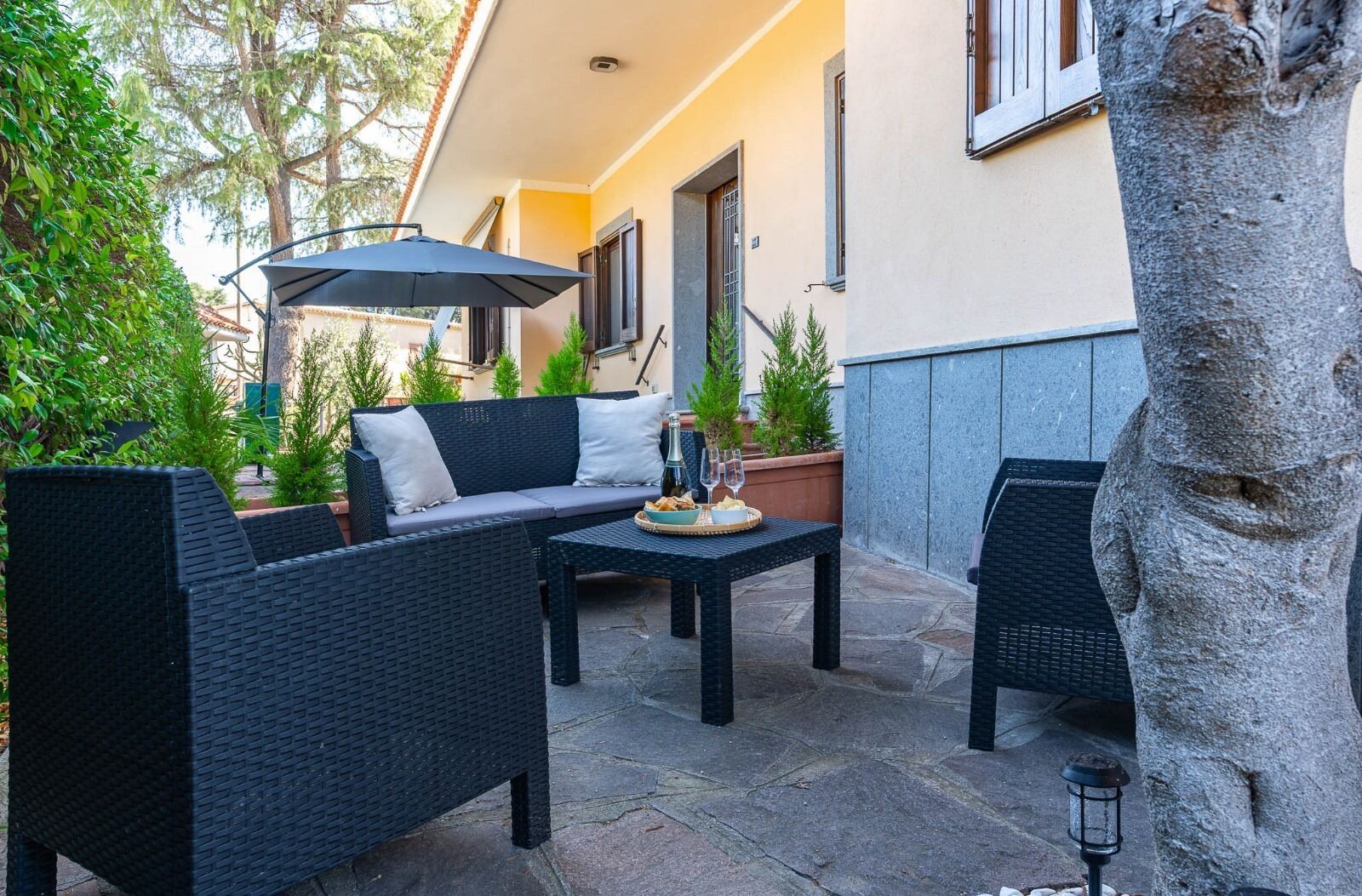 An outdoor patio with wicker furniture, a table with snacks and drinks, and a potted plant.