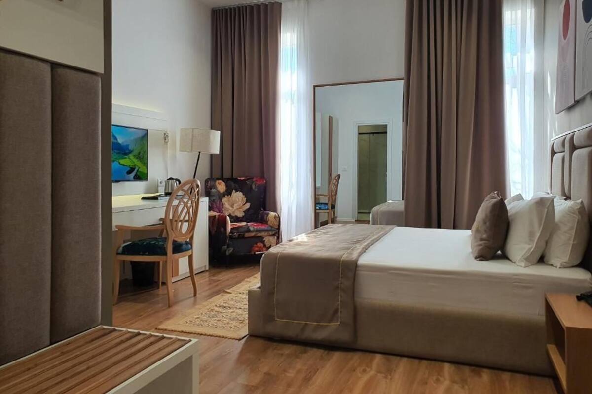 Una habitación de hotel con cama, escritorio, silla y televisor.