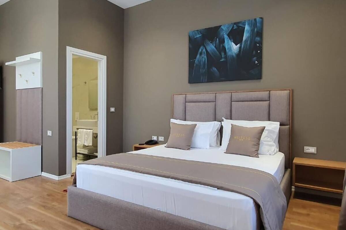 Un dormitorio moderno con una cama grande, cabecera y un cuadro en la pared.