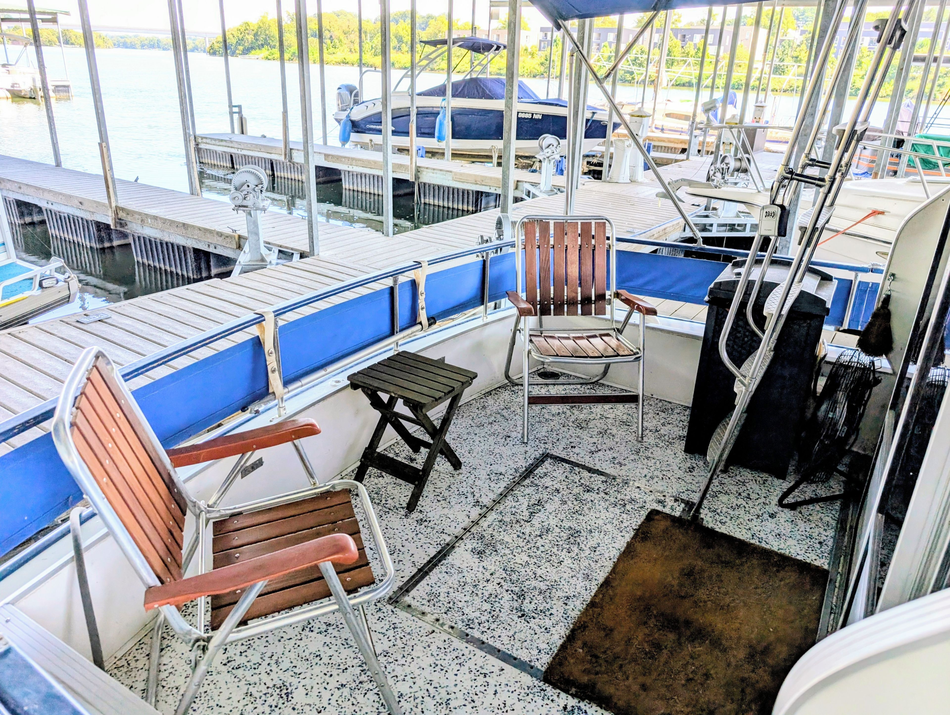 A boat deck with seating, a small table, and a view of the water.