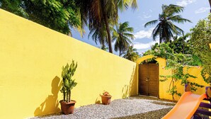 A yellow wall with a wooden door, a gravel path, and a slide. - Casa Amarela em Icaraí de Amontada (Amontada)
