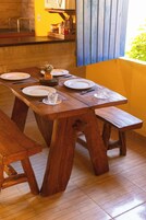 Uma mesa de jantar de madeira com bancos, pratos e talheres.