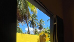 A window view of a yellow wall, a door, and a palm tree. - Casa Amarela em Icaraí de Amontada (Amontada)