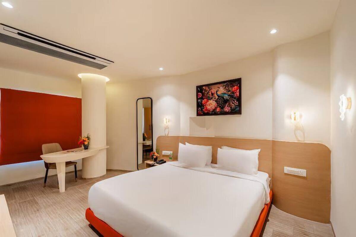 Ein Hotelzimmer mit einem großen Bett, einem Schreibtisch, einem Stuhl und einem Gemälde an der Wand.