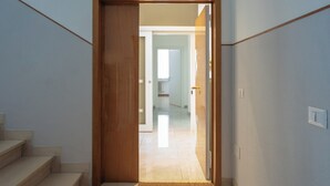 A hallway with a wooden door leading to a room with a tiled floor and a visible radiator. - Elegant 2 Suites Residence,city centre,near Famous Castrocaro Thermal Baths (Castrocaro Terme)