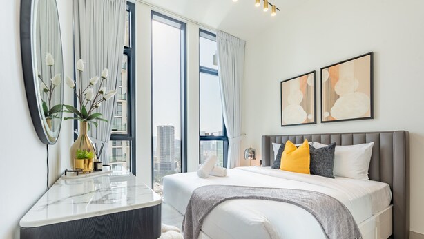 Une chambre moderne avec un grand lit, une table de chevet et un miroir.