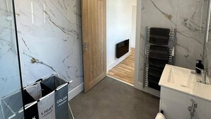 A modern bathroom with marble walls, a wooden door, a built-in towel rack, and a visible laundry bag. - 6 Guests/free Parking/old Trafford/20min City (Manchester)