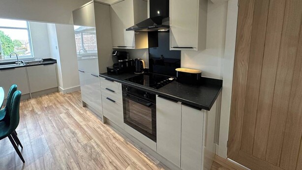 A modern kitchen with white cabinets, a black countertop, and a built-in oven. - 6 Guests/free Parking/old Trafford/20min City (Manchester)