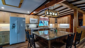 Una cocina con armarios de madera, un refrigerador blanco, un microondas, una estufa y una isla grande con taburetes de bar.