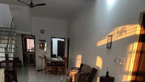 A spacious living area with a tiled floor, a dining table, and several chairs. - Wilder Lust Homestay (Bhira)