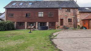 A two-story house with a stone facade, a wooden exterior, and a sloped roof. - Millbarn (Taunton)