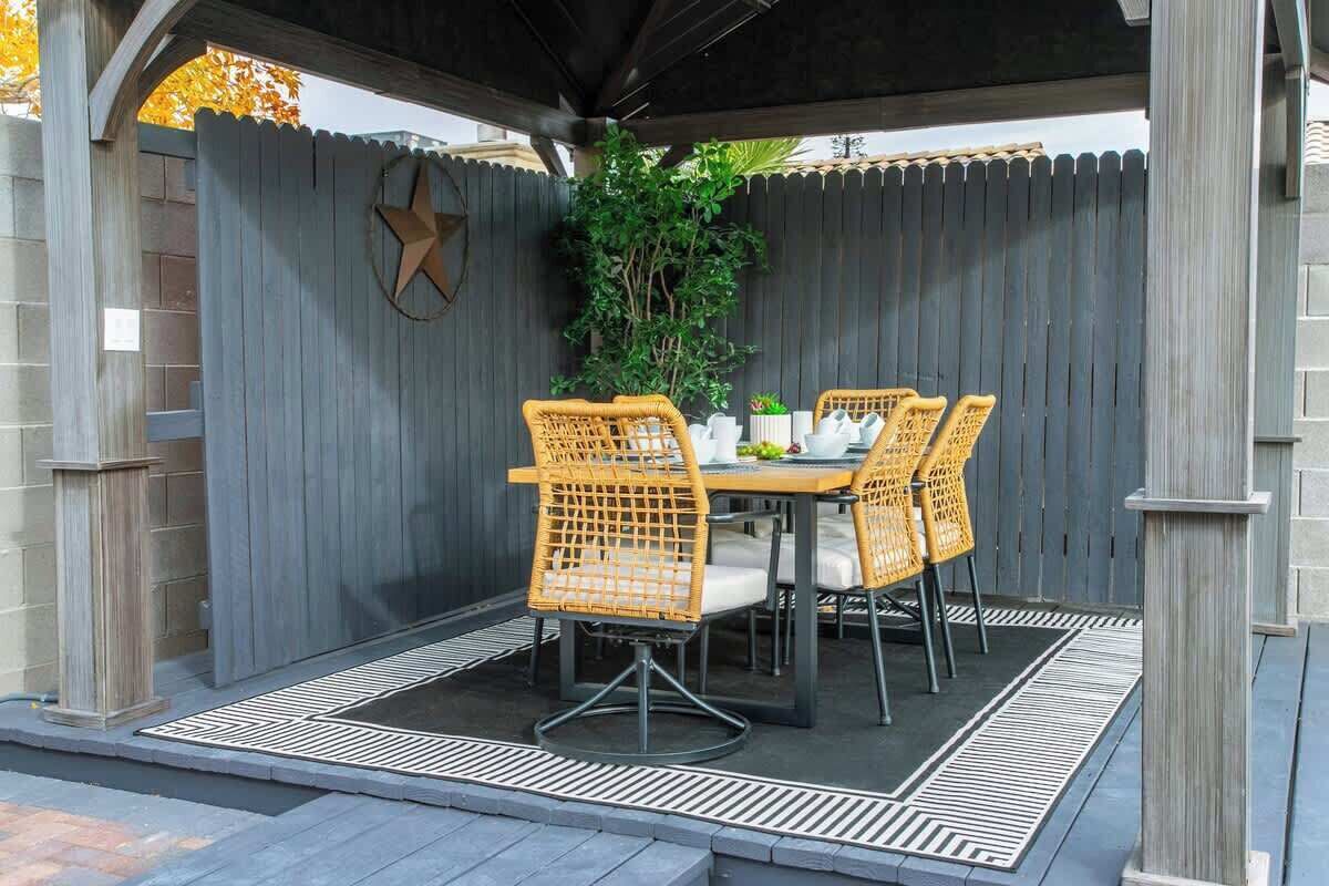 An outdoor patio with a table and four chairs, surrounded by a wooden fence and a star decoration.