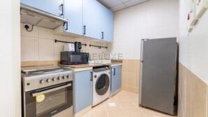Een kleine keuken met een inbouwoven, magnetron en wasmachine.