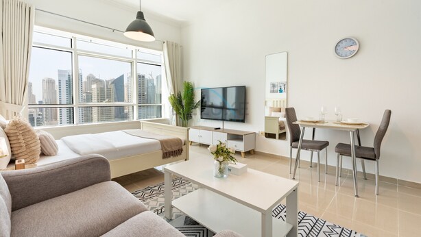 Een moderne woonkamer met een bank, een eettafel met stoelen, een televisie en een groot raam met uitzicht over de stad.