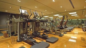 Een sportschool met diverse fitnessapparaten, waaronder loopbanden en elliptische trainers, netjes opgesteld in rijen.
