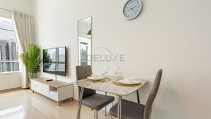 Een moderne eetruimte met een tafel gedekt voor twee personen, een televisie en een klok aan de muur.