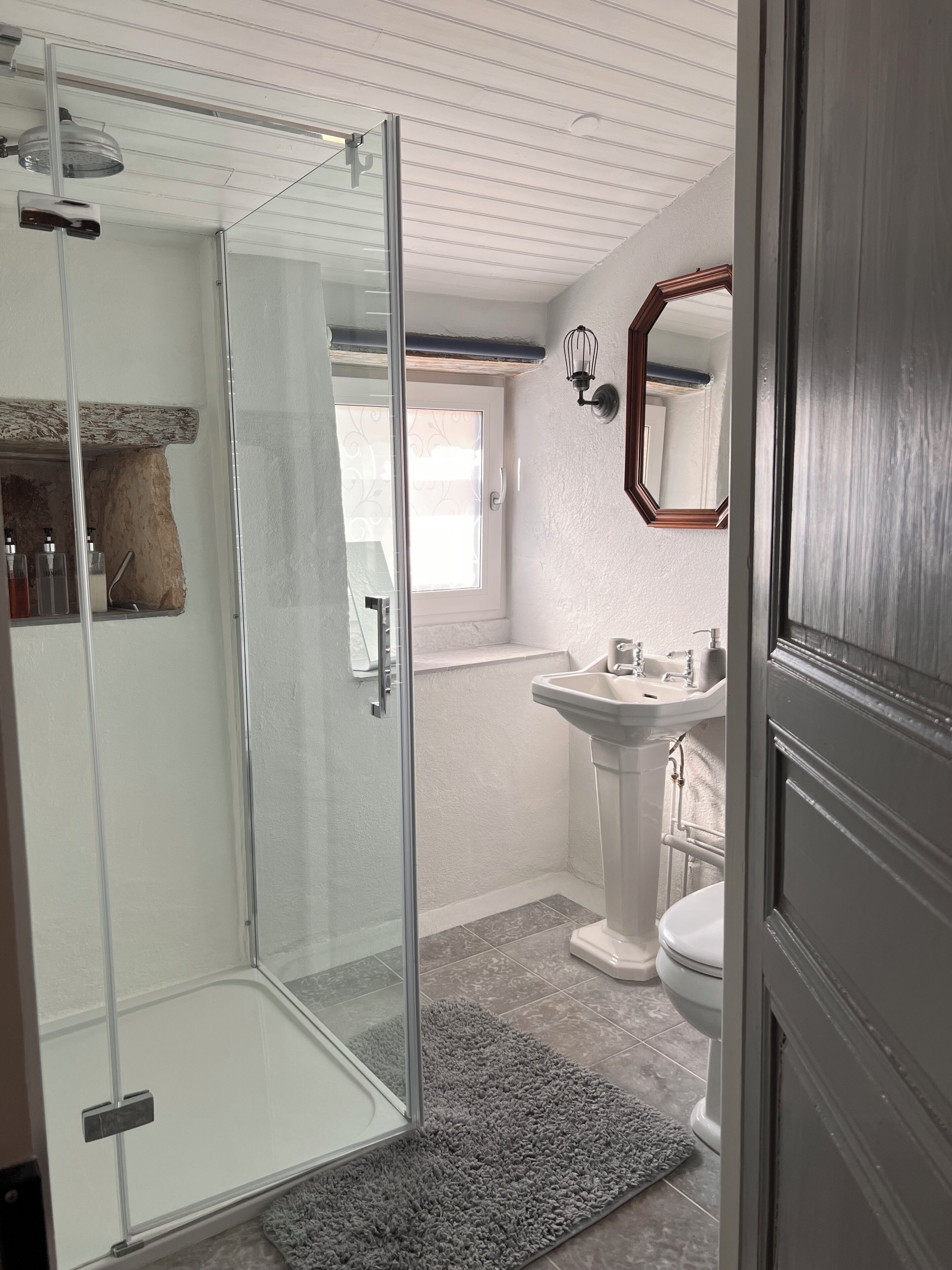 Ein Badezimmer mit Duschkabine aus Glas, einem Standwaschbecken und einer Toilette.